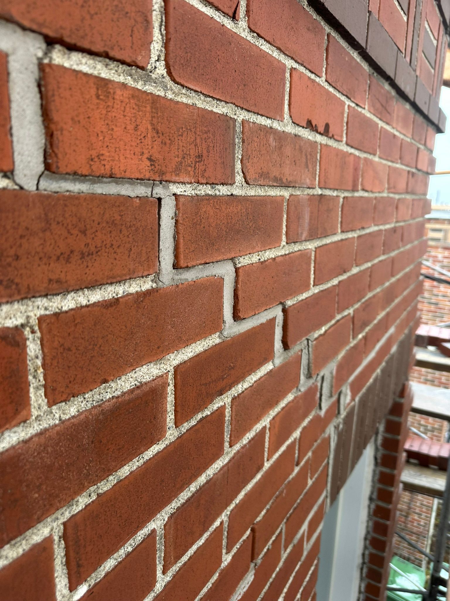 Mur en briques rouges avec des fissures dans le mortier.