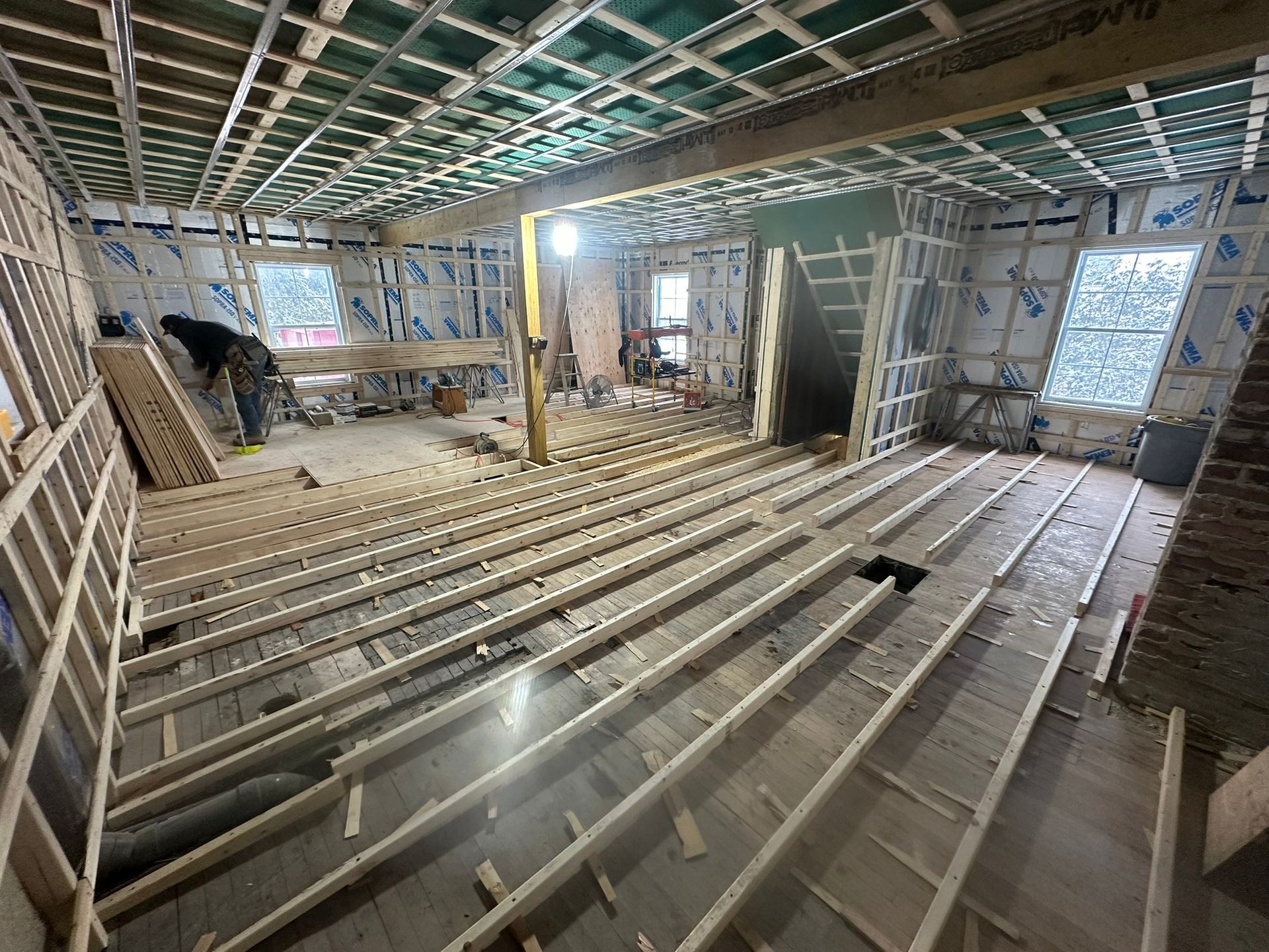 Construction intérieure : Ossature bois pour le plancher, les murs et le plafond. Une personne travaille sur le projet.