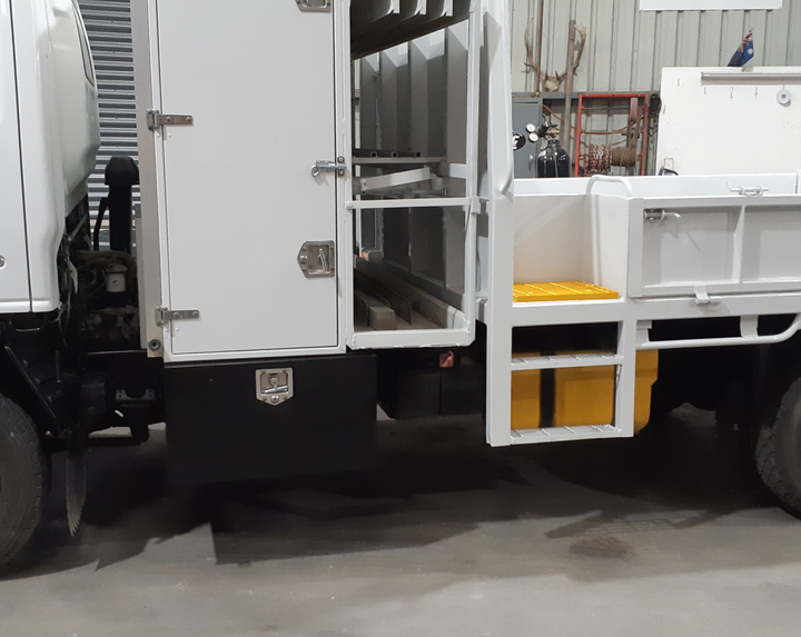 A white truck with the doors open is parked in a garage.