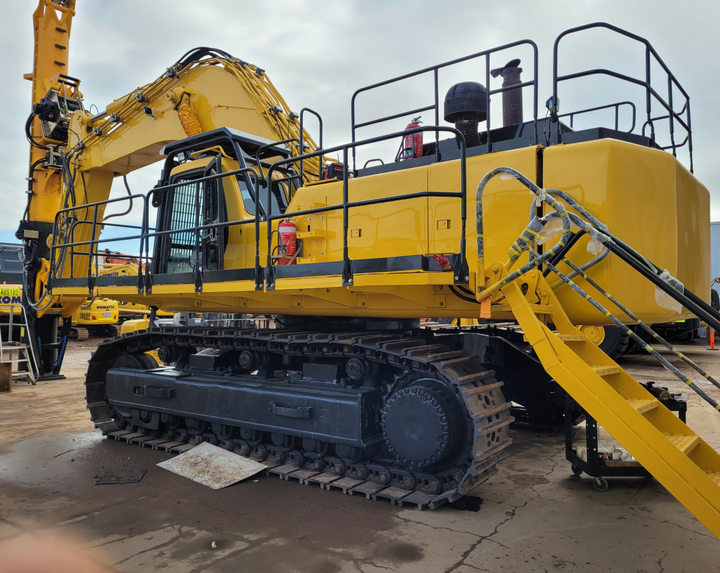 A large yellow excavator is parked in a parking lot.
