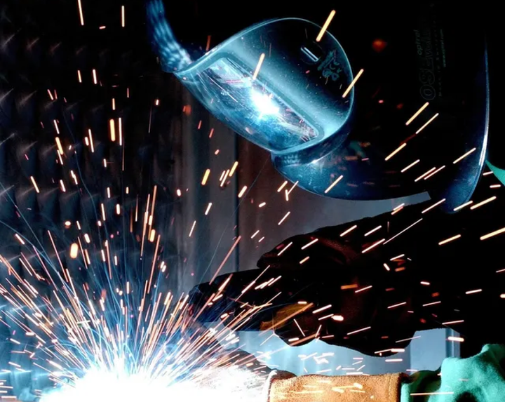 A man is welding a piece of metal with sparks coming out of it