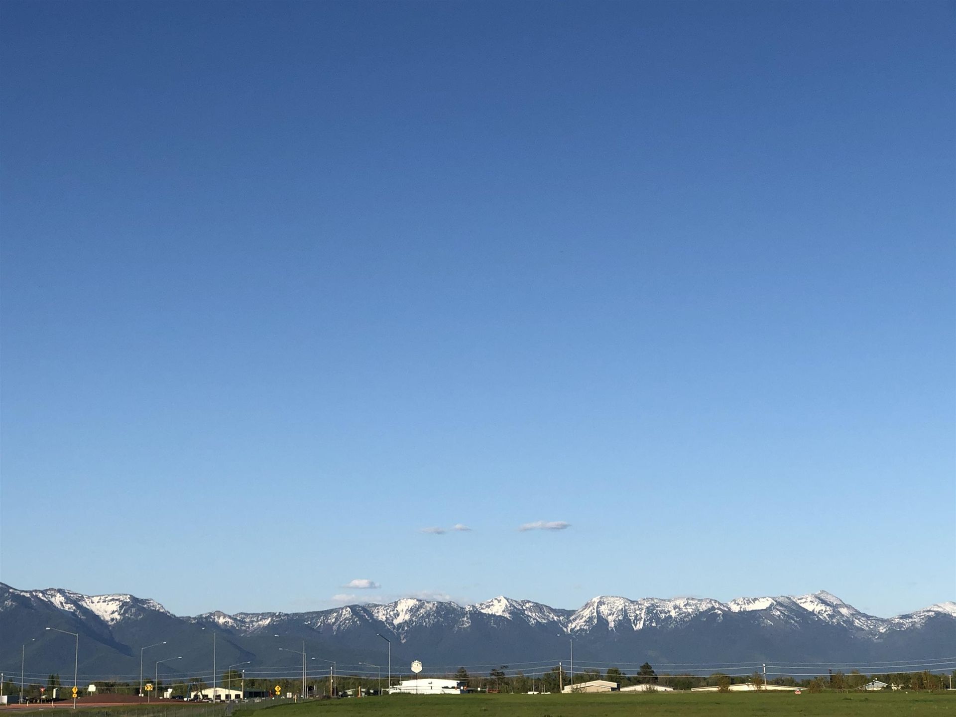 Snow-capped mountains beneath a clear blue sky over a rural landscape