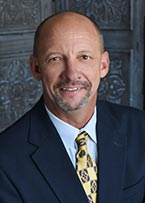 A man in a suit and tie is smiling for the camera.