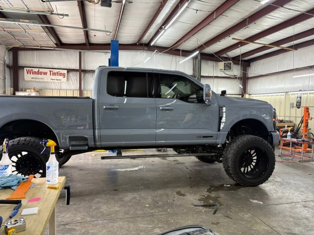 Lifted gray pickup truck in a workshop with its hood open on a lift.