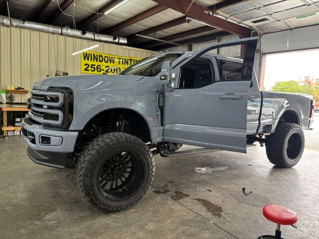 Gray lifted pickup truck in a garage, with oversized tires and open driver door