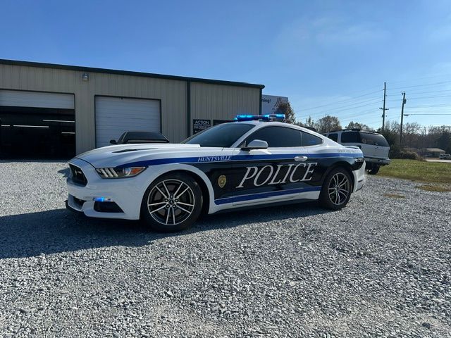 Police car parked outside a garage on gravel under a clear sky