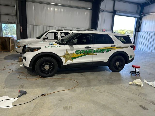White sheriff SUV with green star decals parked inside a garage, with a red stool and cleaning items nearby