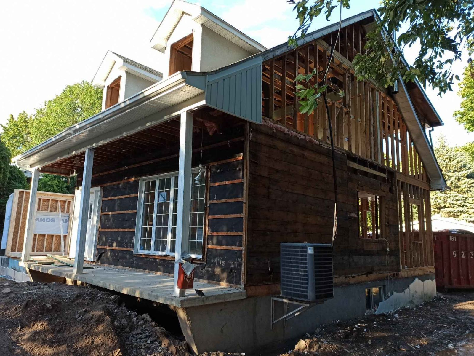 Une maison est en construction avec un porche et beaucoup de fenêtres.