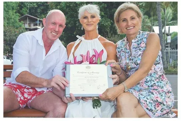 A Man and Two Women Are Sitting on a Bench Holding a Certificate โ GinaS Cairns Tropical Weddings in Parramatta Park, QLD