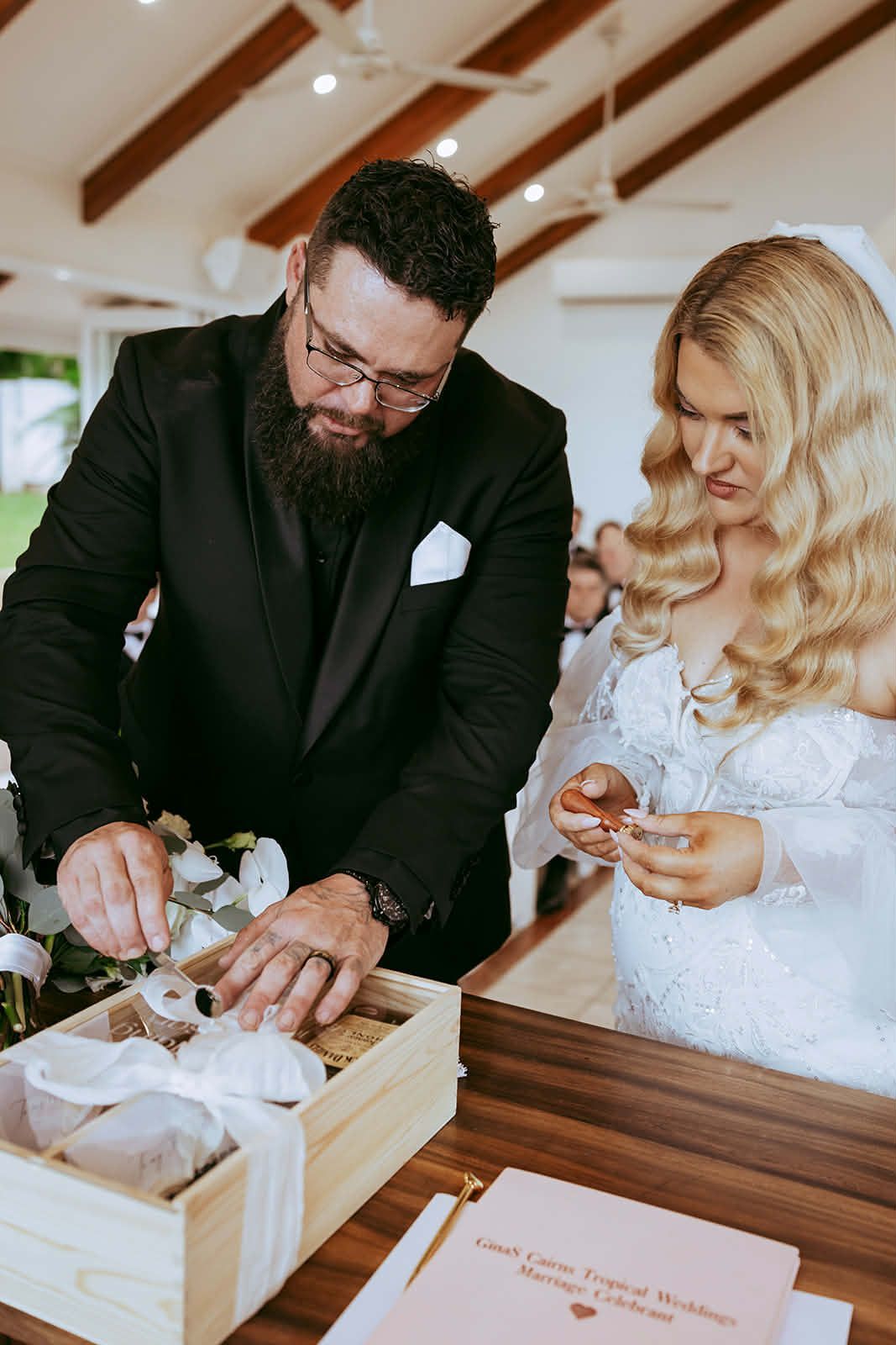 Couple cutting a white-frosted cake at a wedding reception table