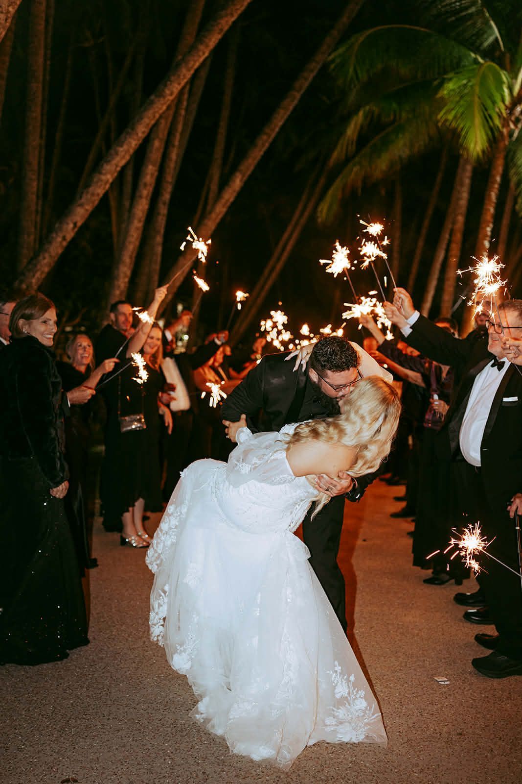 Bride and groom kiss under sparklers at an outdoor nighttime wedding reception
