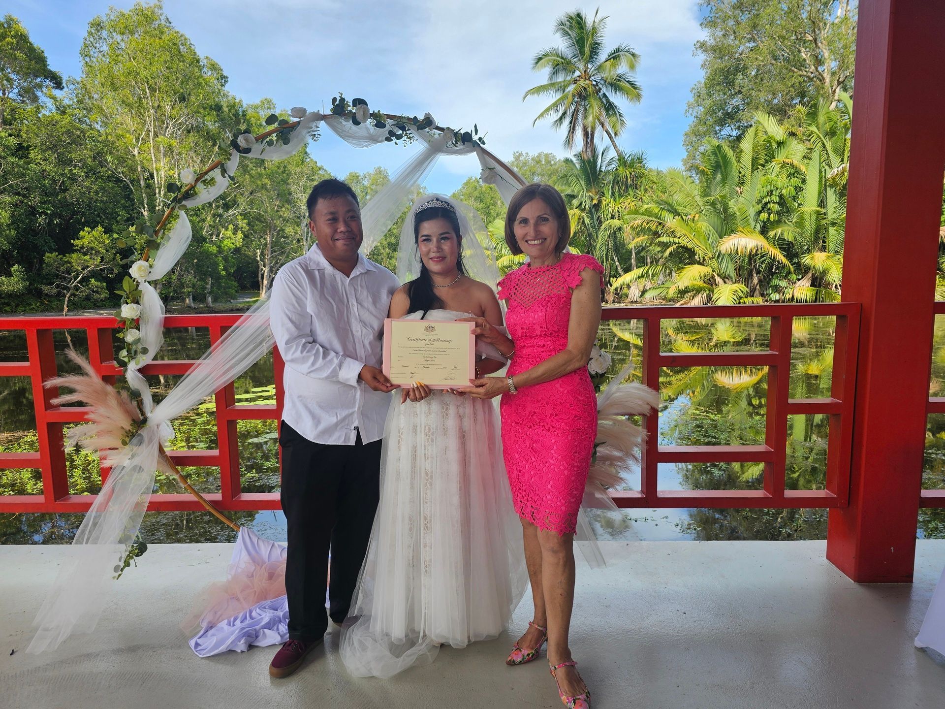 Three people posing with a certificate on a red balcony — GinaS Cairns Tropical Weddings in Parramatta Park, QLD