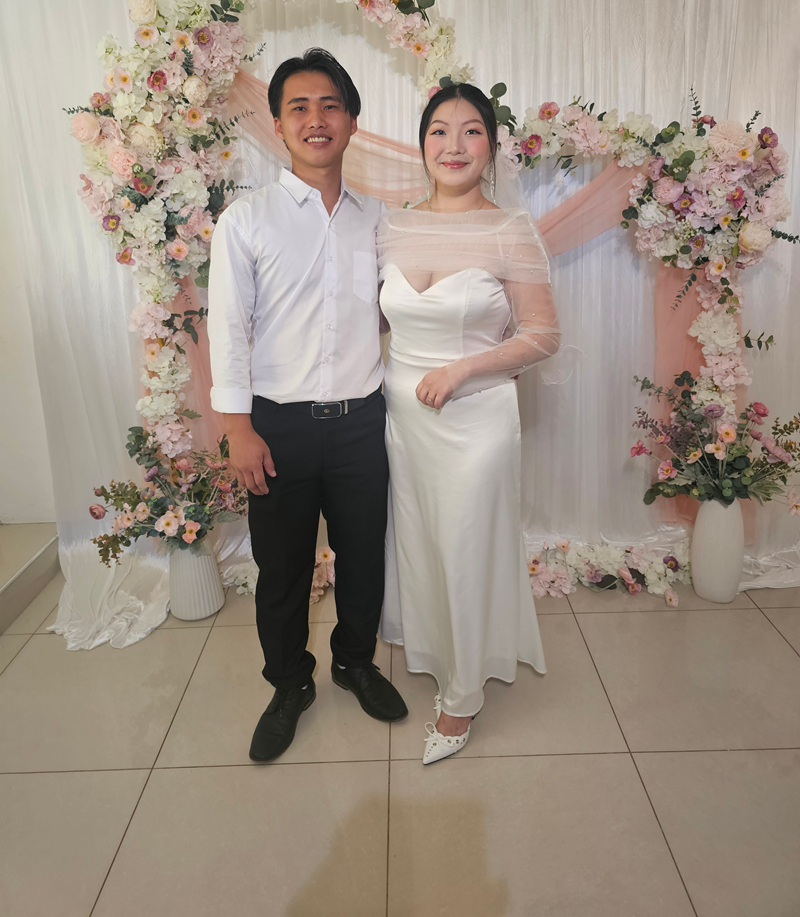 Two people posing at a floral wedding backdrop — GinaS Cairns Tropical Weddings in Parramatta Park, QLD