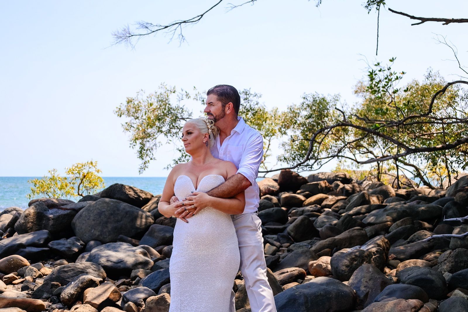 Couple in wedding attire standing on rocks outdoors beneath a tree — GinaS Cairns Tropical Weddings in Parramatta Park, QLD