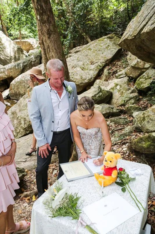 A Bride and Groom Are Signing a Wedding Certificate Beside the River โ GinaS Cairns Tropical Weddings in Parramatta Park, QLD