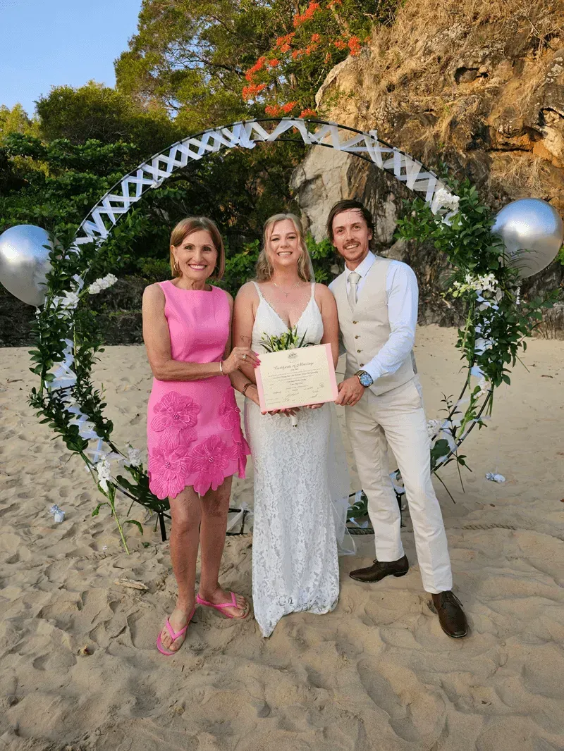 Three people posing on a beach under a floral arch — GinaS Cairns Tropical Weddings in Parramatta Park, QLD