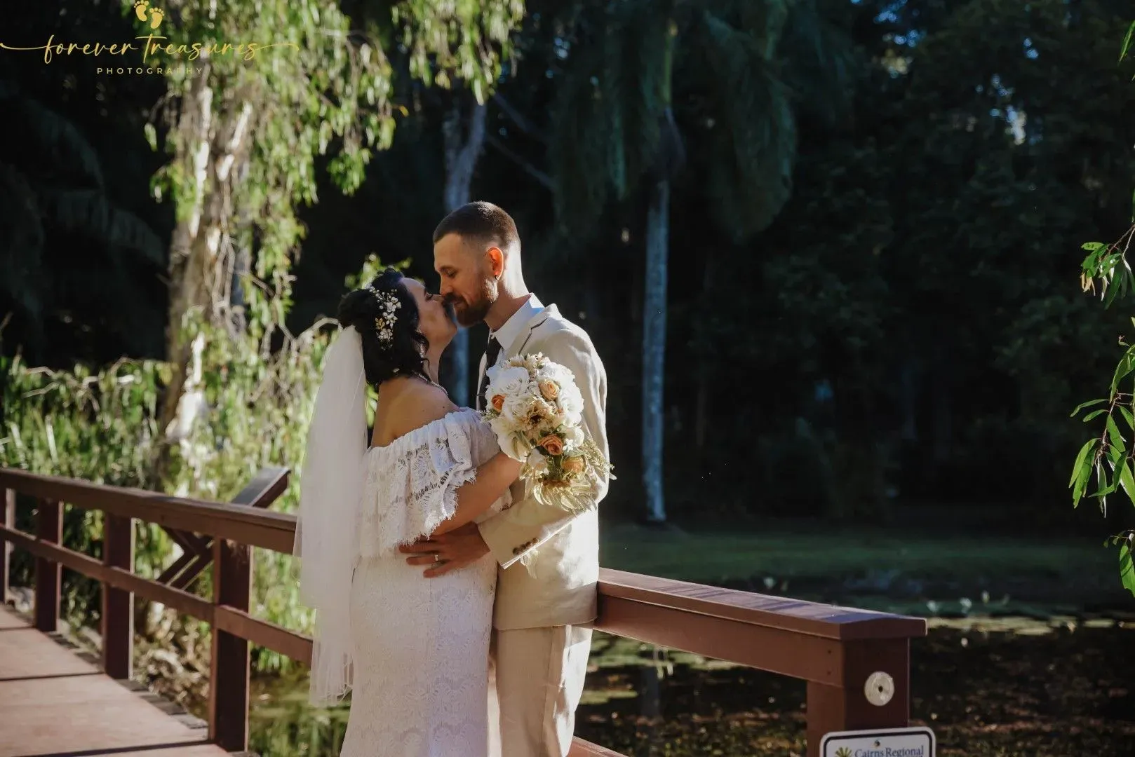 A Bride and Groom Are Kissing on a Wooden Bridge โ GinaS Cairns Tropical Weddings in Parramatta Park, QLD