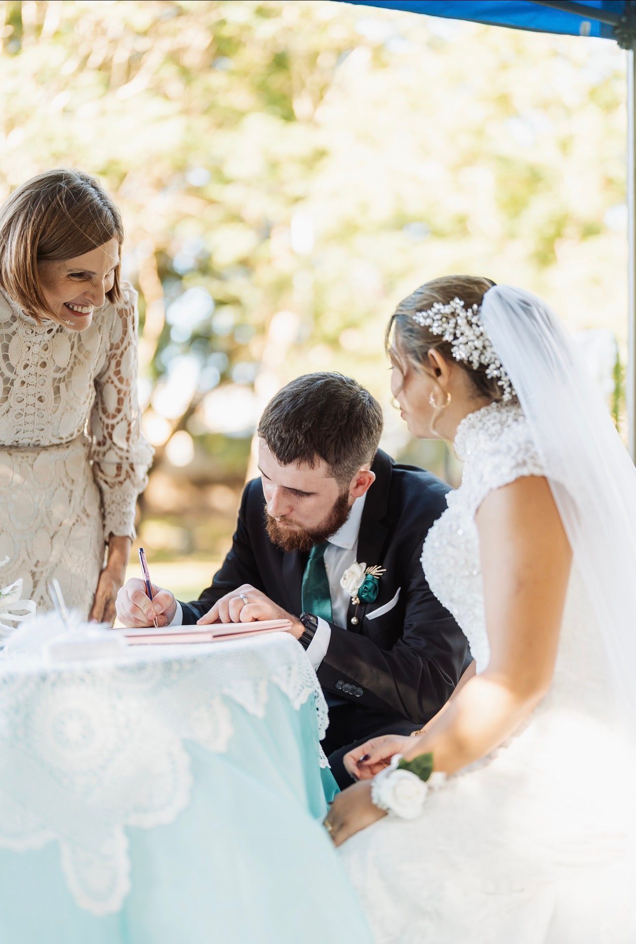 Outdoor wedding ceremony with couple signing a document while officiant watches