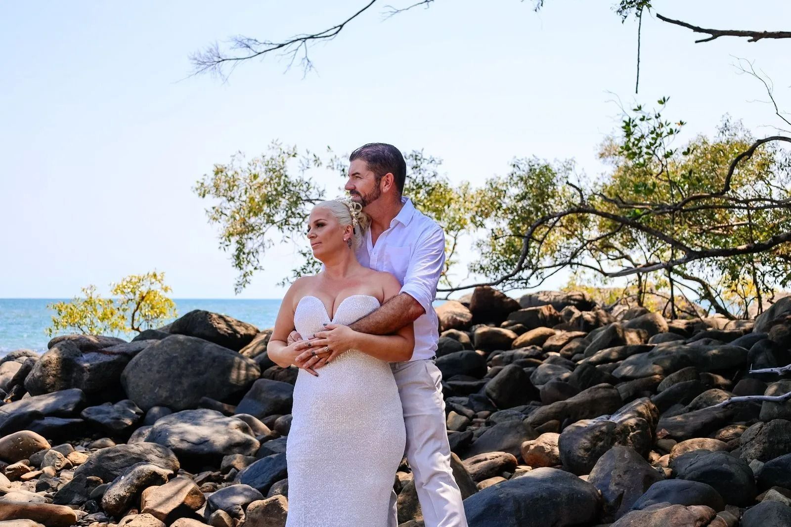 Couple in White Wedding Attire Posing on Rocky Shoreline Under a Tree — GinaS Cairns Tropical Weddings in Parramatta Park, QLD