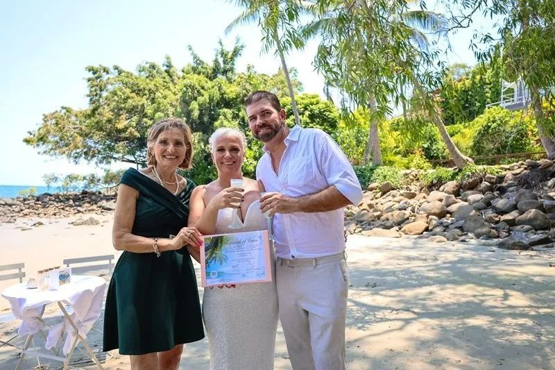 Corrina and Json with Gina Smiling and Holding Drinks on A Sunny Beach — GinaS Cairns Tropical Weddings in Parramatta Park, QLD