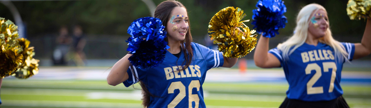 A group of cheerleaders are posing for a picture with the beckman belle 's logo in the background