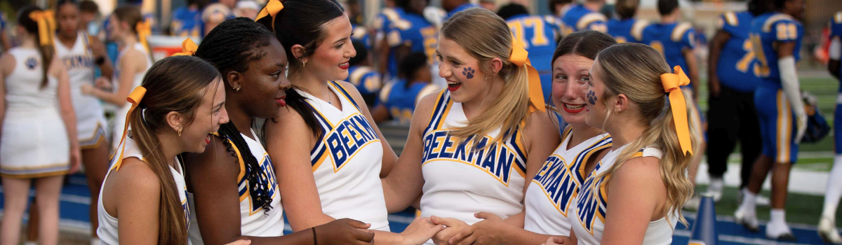 A group of cheerleaders are standing next to each other on a field.