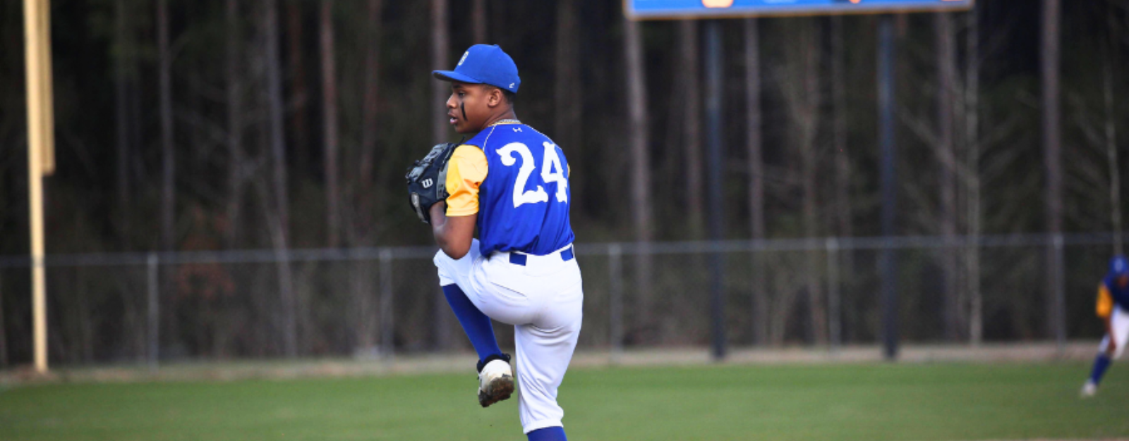 A baseball player in a blue uniform with the number 24 on his back is pitching the ball.