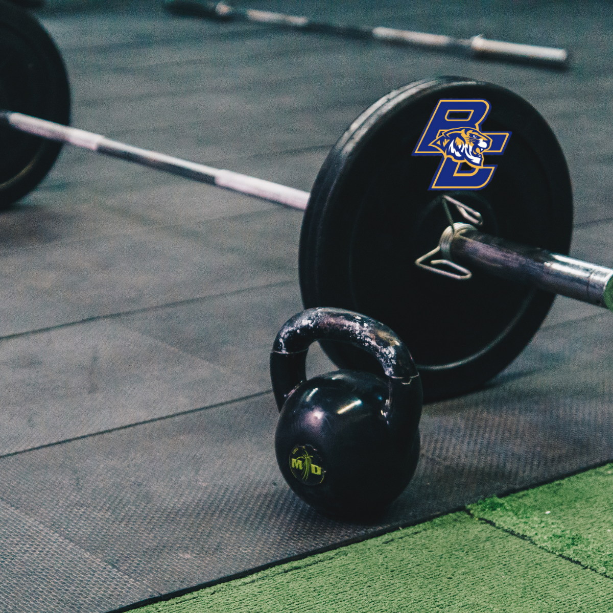 A barbell and a kettlebell are on the floor in a gym