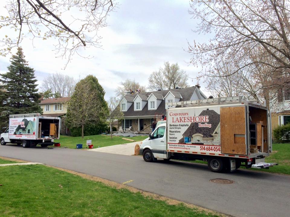 Deux camions de déménagement stationnés dans une rue résidentielle, devant une maison.