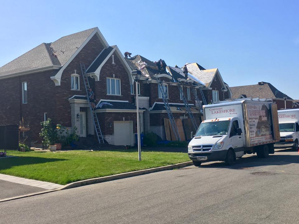 Maison en cours de réfection de la toiture, échelles, camion blanc garé dans la rue.