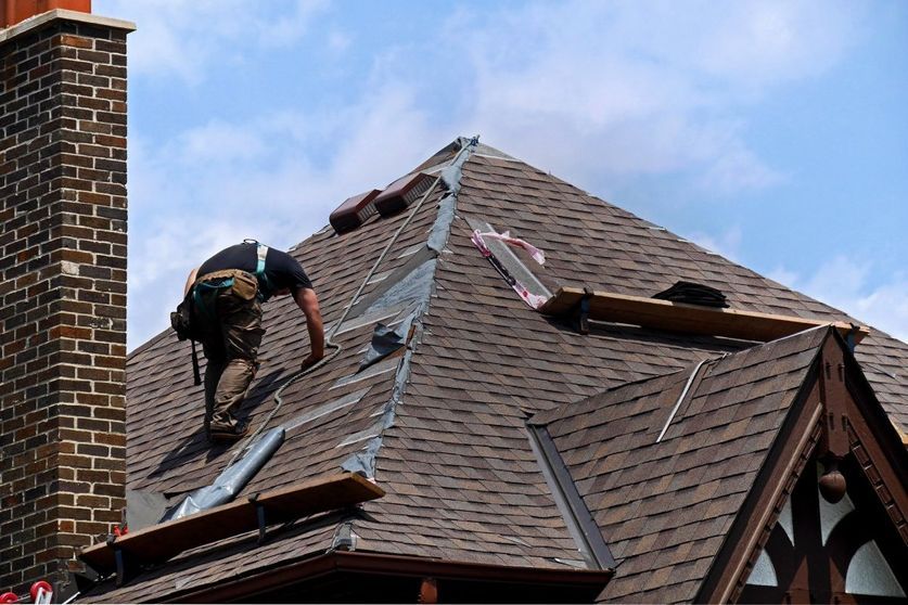 A man is working on the roof of a house.