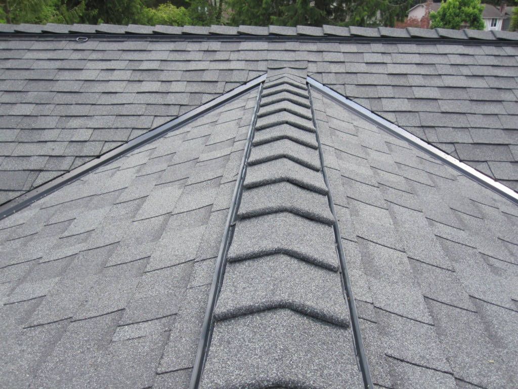 Toiture en bardeaux gris avec une arête centrale, des solins métalliques et des bardeaux qui se chevauchent.