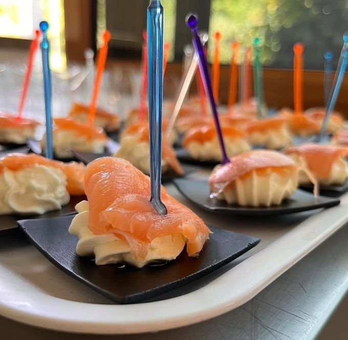 Tartine di salmone affumicato su piatti neri con bandierine colorate su stuzzicadenti a un buffet