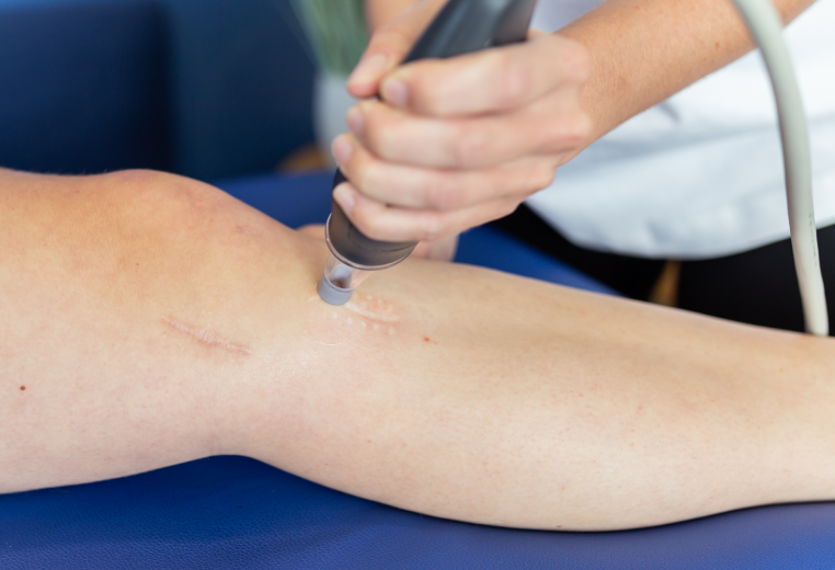 Healthcare worker using a handheld device on a patient’s leg during a medical examination