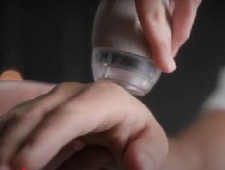 Close-up of a hand holding a clear bottle over another hand, applying liquid on the skin.
