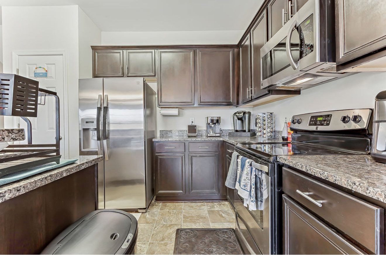 Modern kitchen with stainless steel appliances, dark wood cabinets, and granite countertops