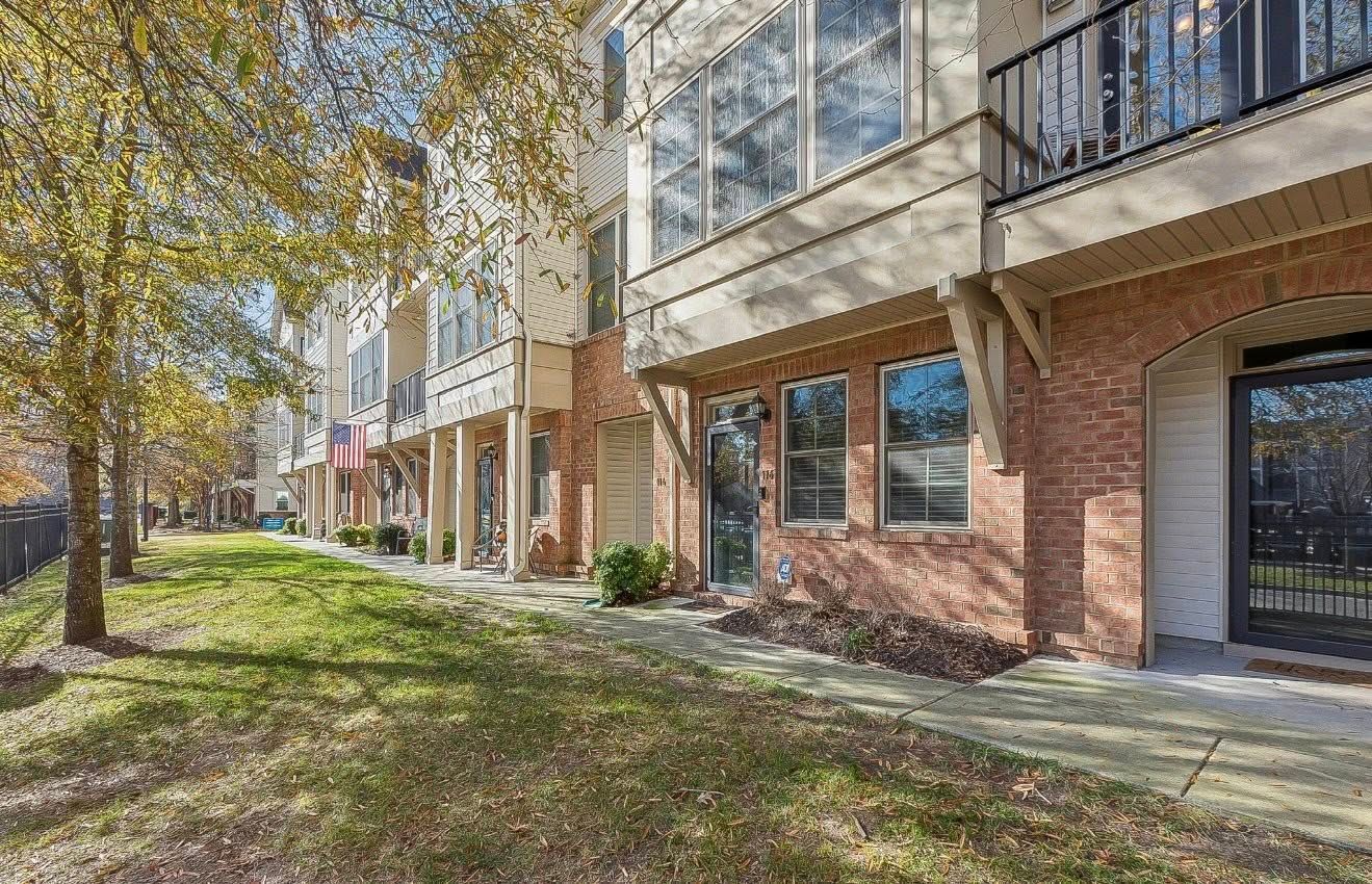 Apartment building with brick and glass facade beside trees and grassy lawn
