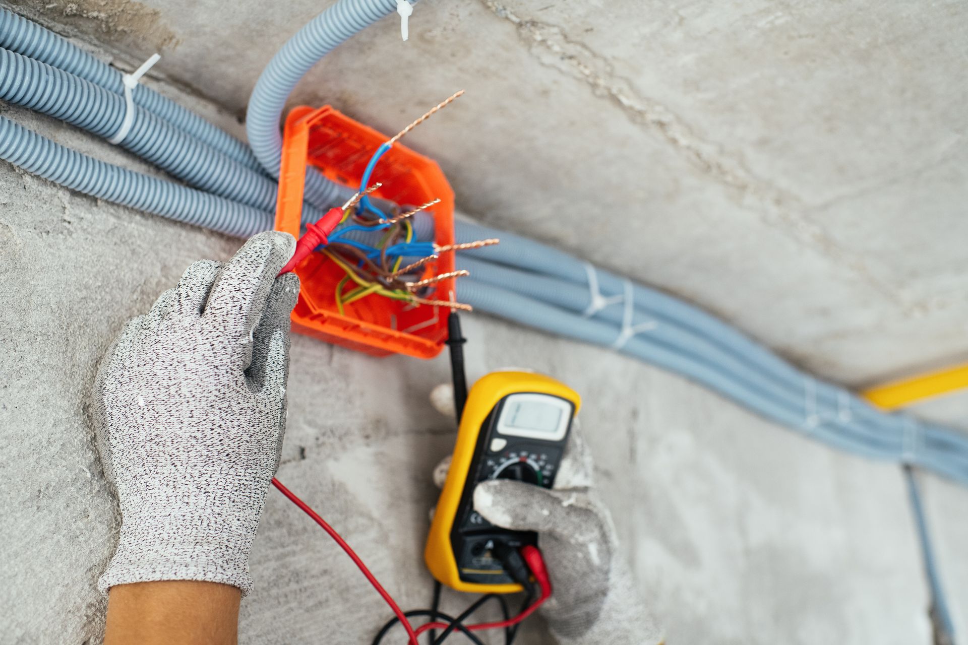 A person is using a multimeter to test a box of wires.