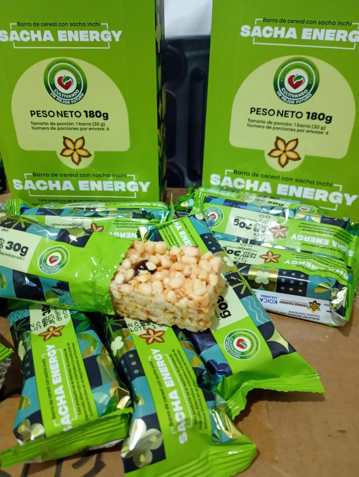 Envase del snack Green Sacha Energy y paquetes dispersos con un vaso transparente de snacks inflados en el centro.