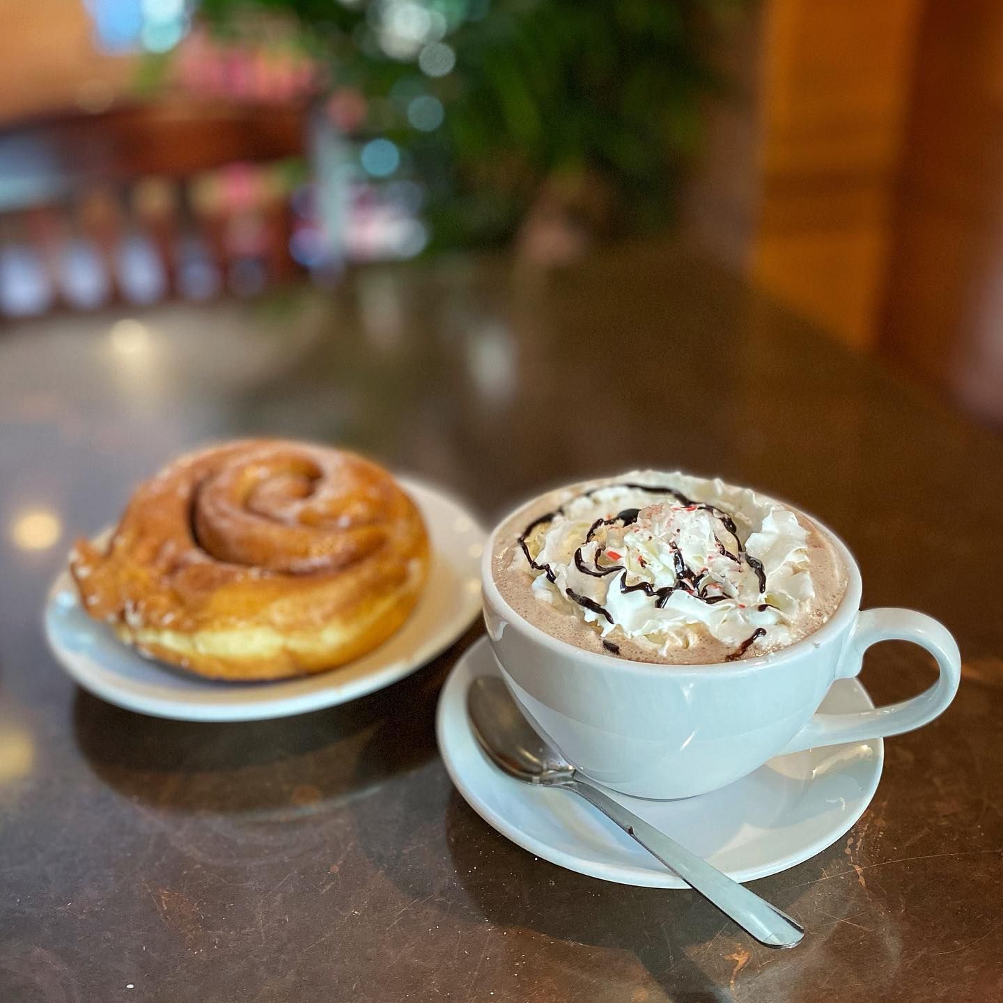 Cinnamon roll next to a cup of hot chocolate