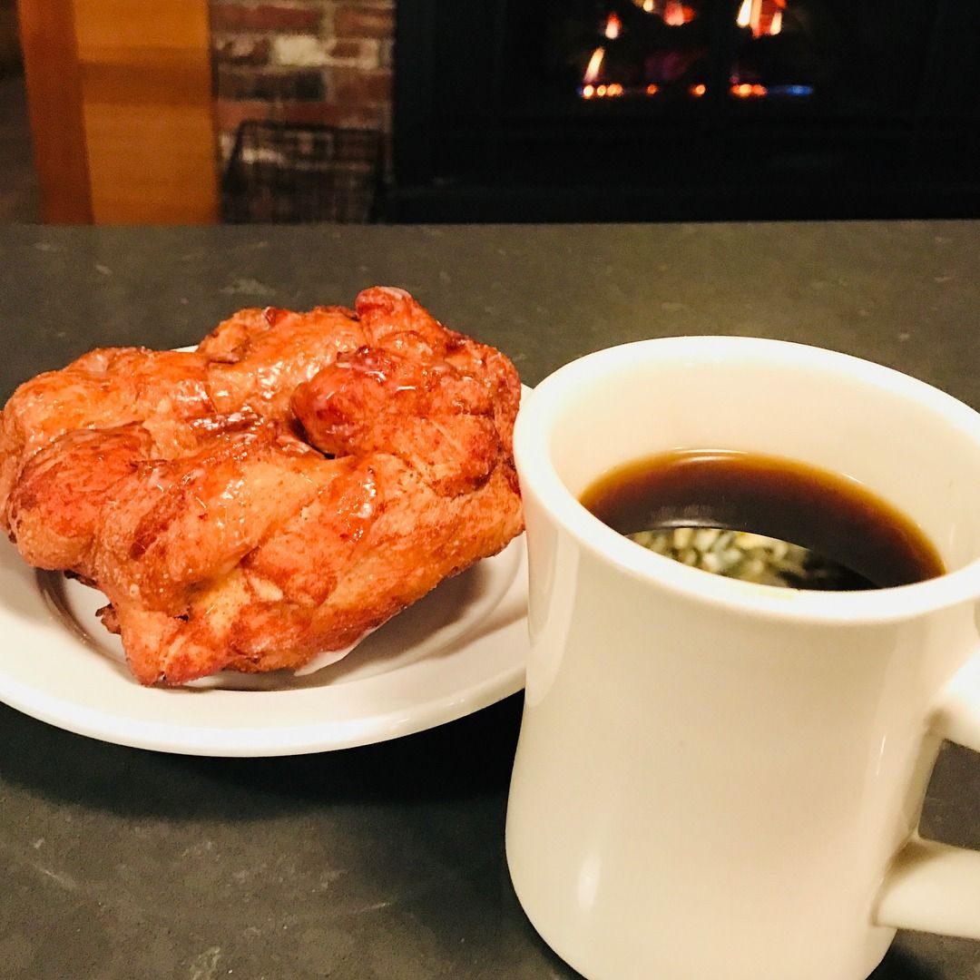 Donut on a plate next to a mug of coffee