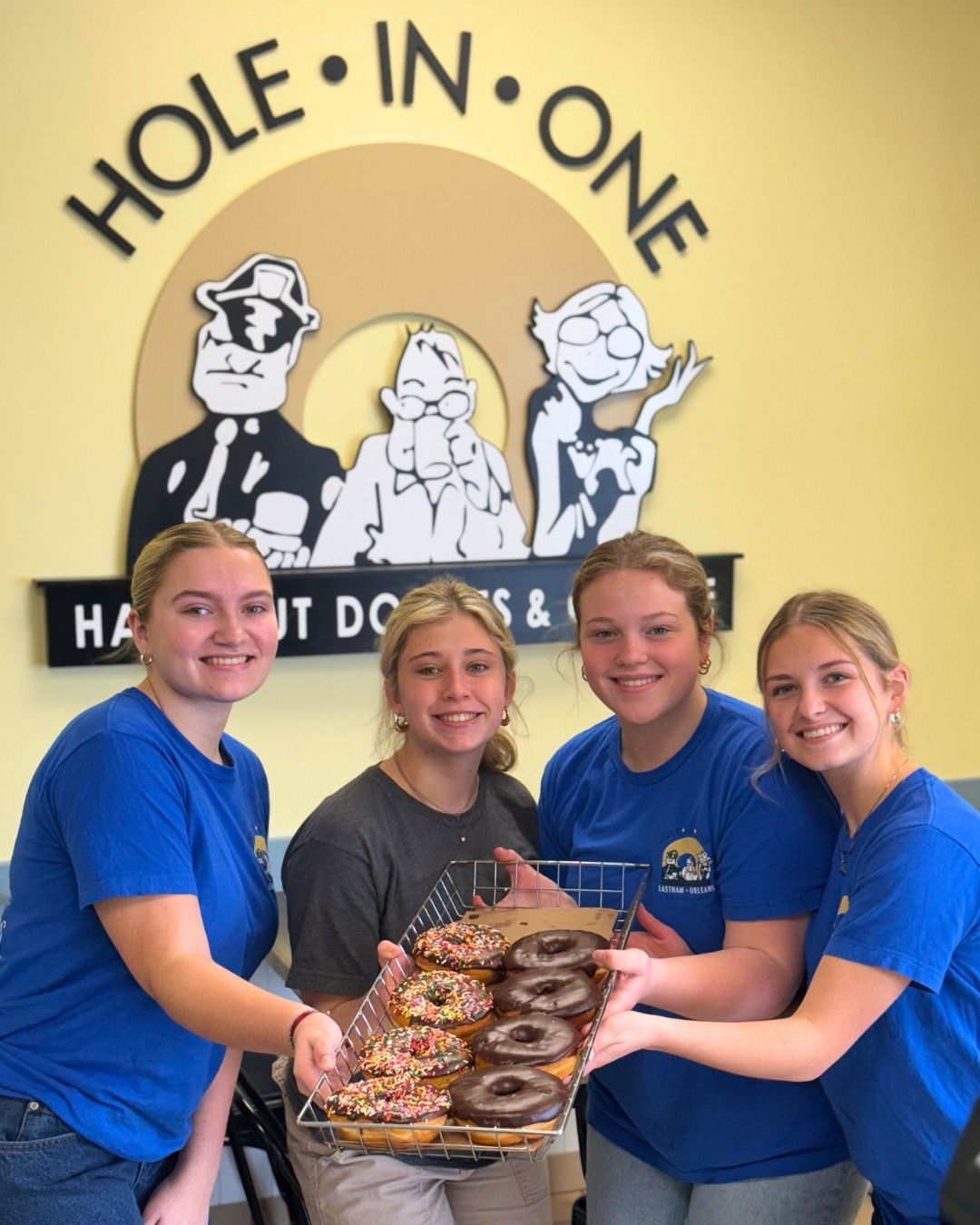 Four people holding tray of donuts