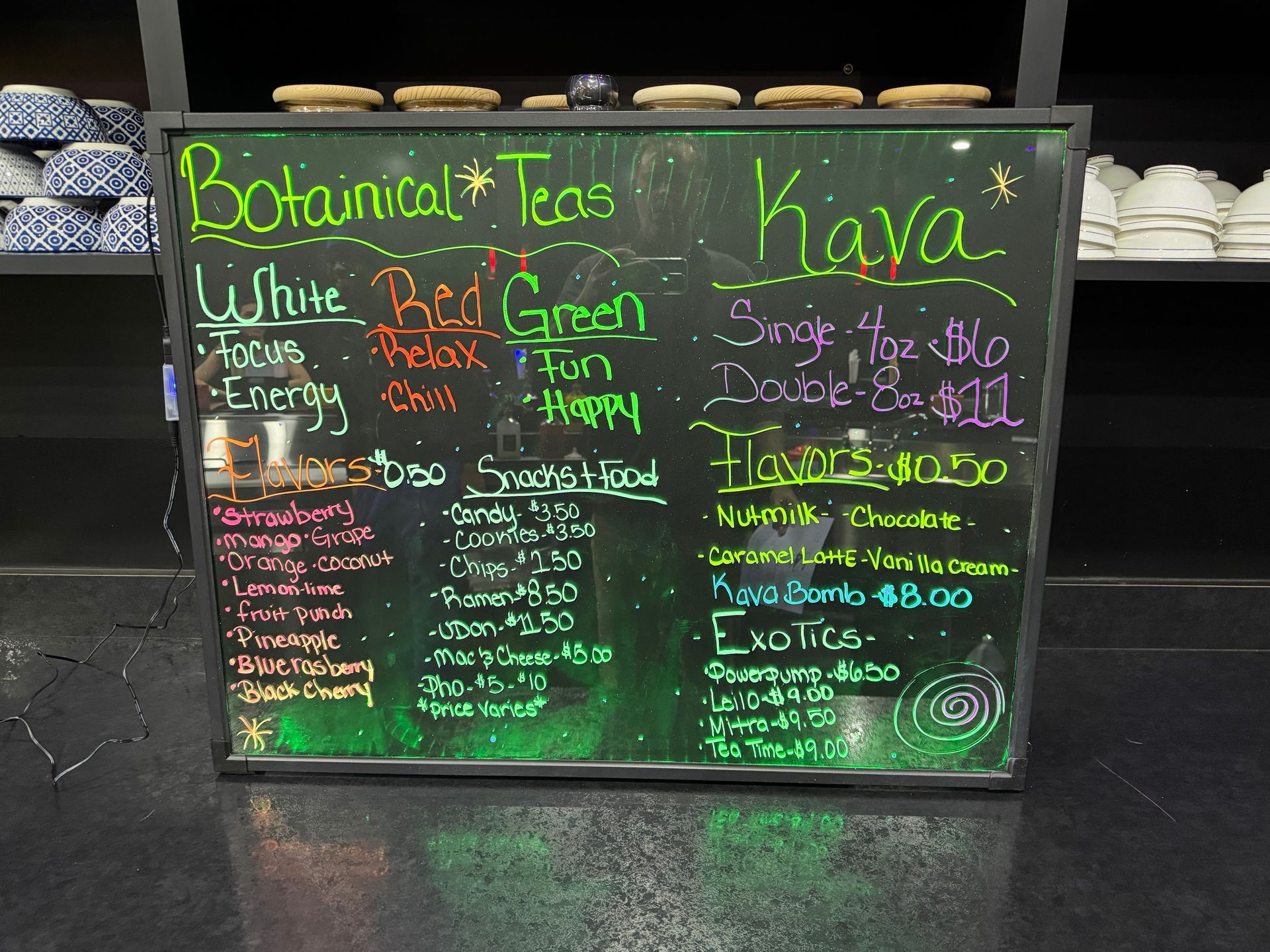 Colorful chalkboard menu for botanical teas and lattes in a café display case