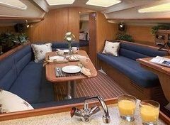 Interior of a sailboat: blue upholstered seating, wooden table, drinks, and a sink.