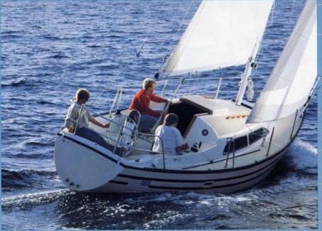 Sailboat on water, three people aboard. White sails, blue water.