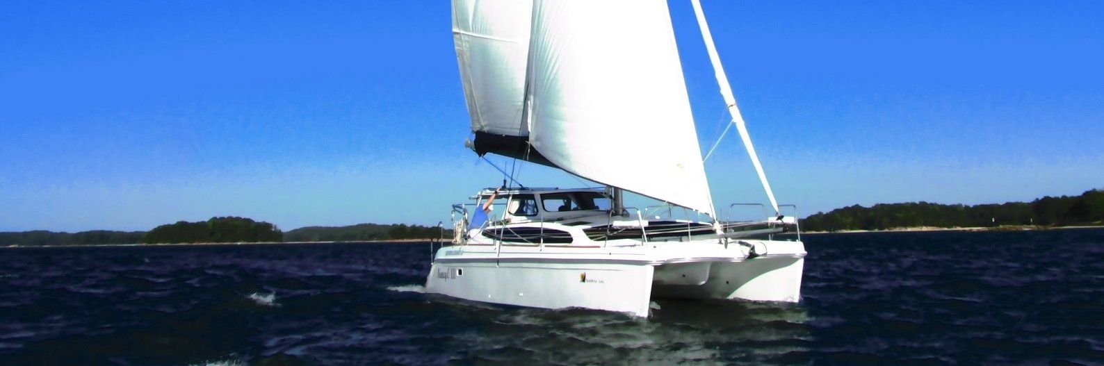 Catamaran sailing on a blue sea under a clear sky.