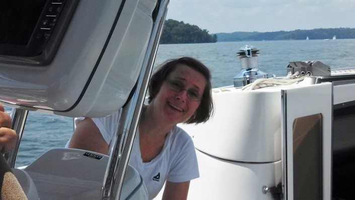 Woman smiling on a boat, lake in the background. Bright sunny day.