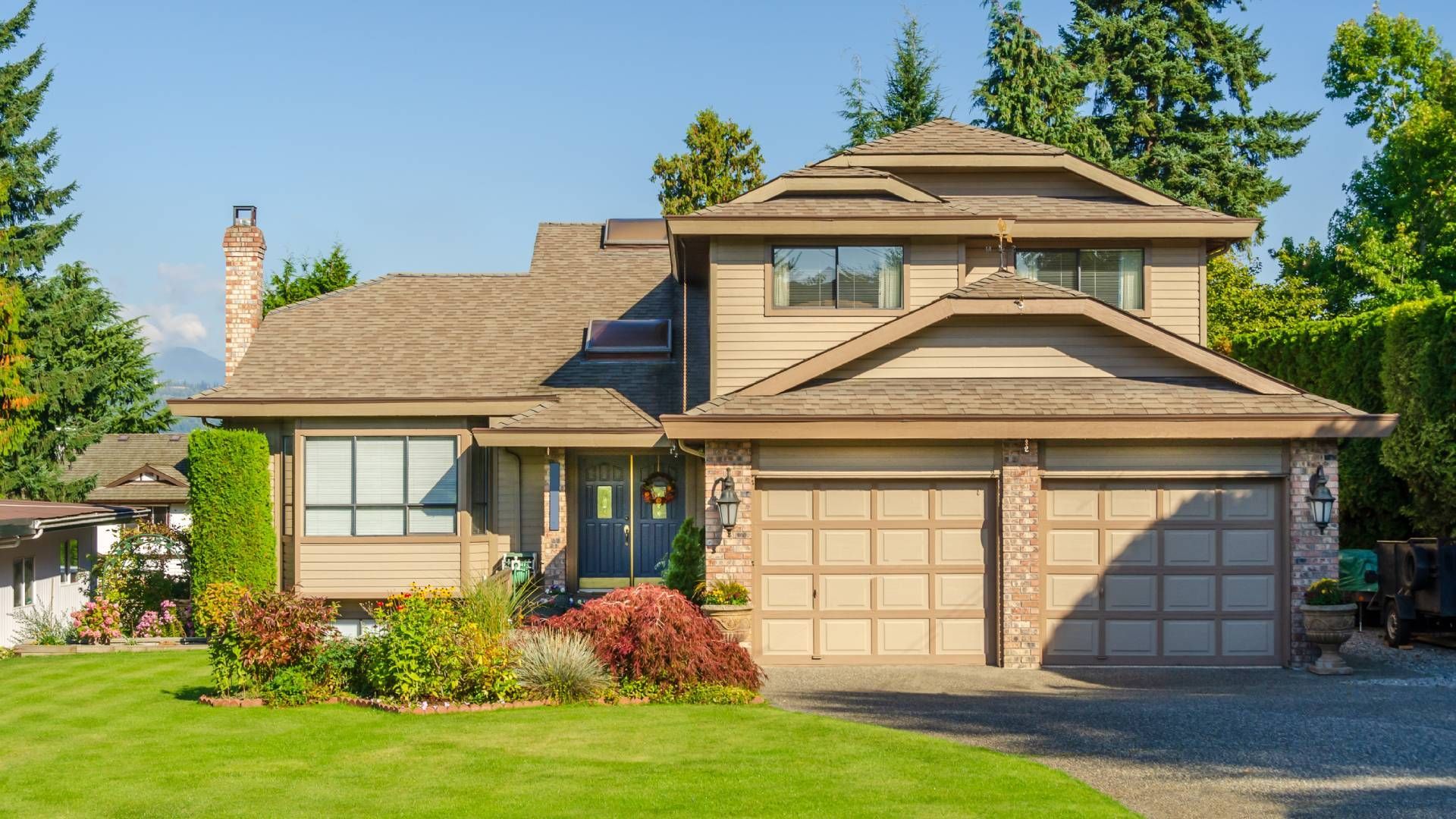 A large house with two garage doors and a lush green lawn