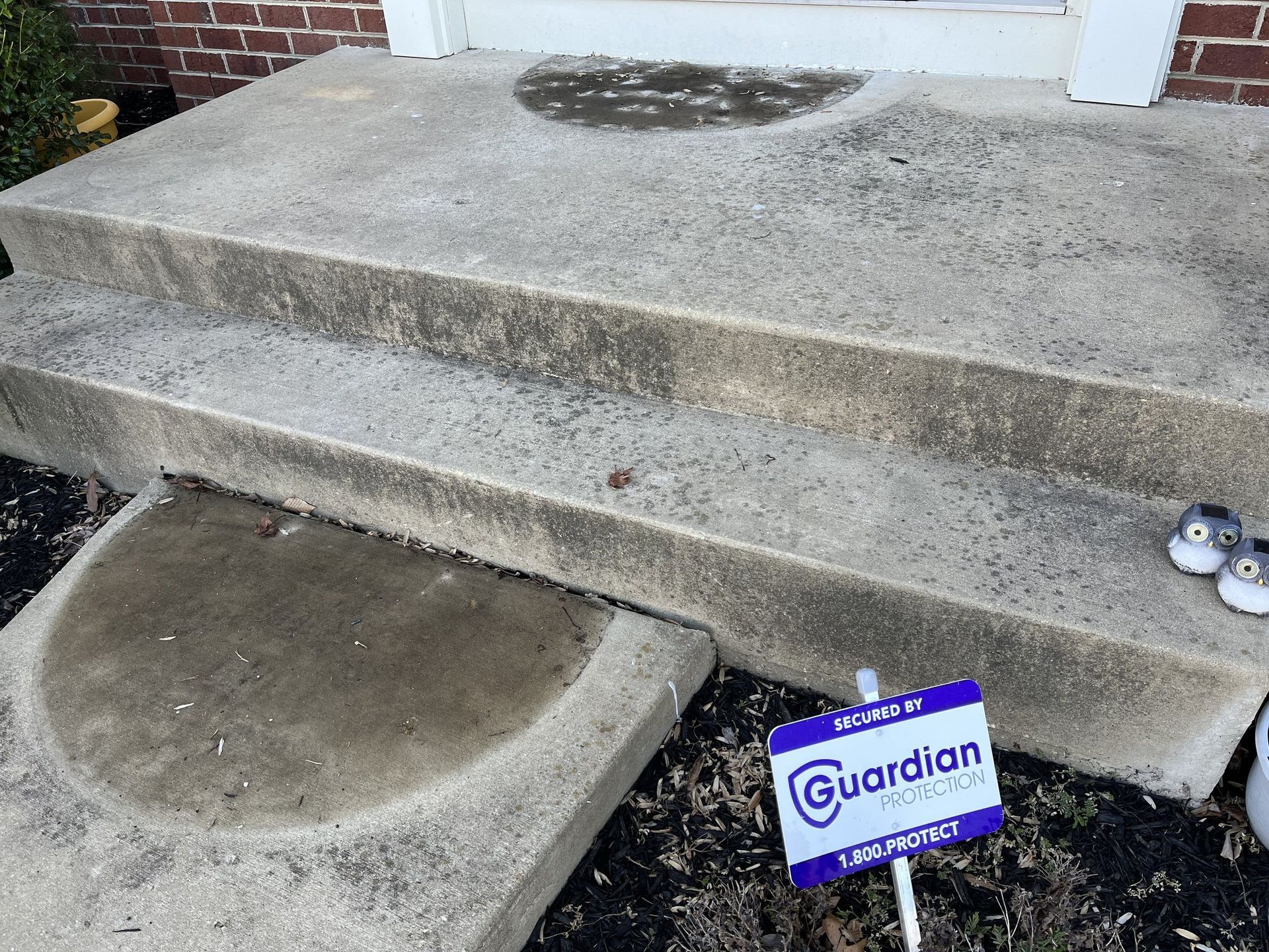 A pair of shoes are sitting on the steps of a house next to a guardian sign.