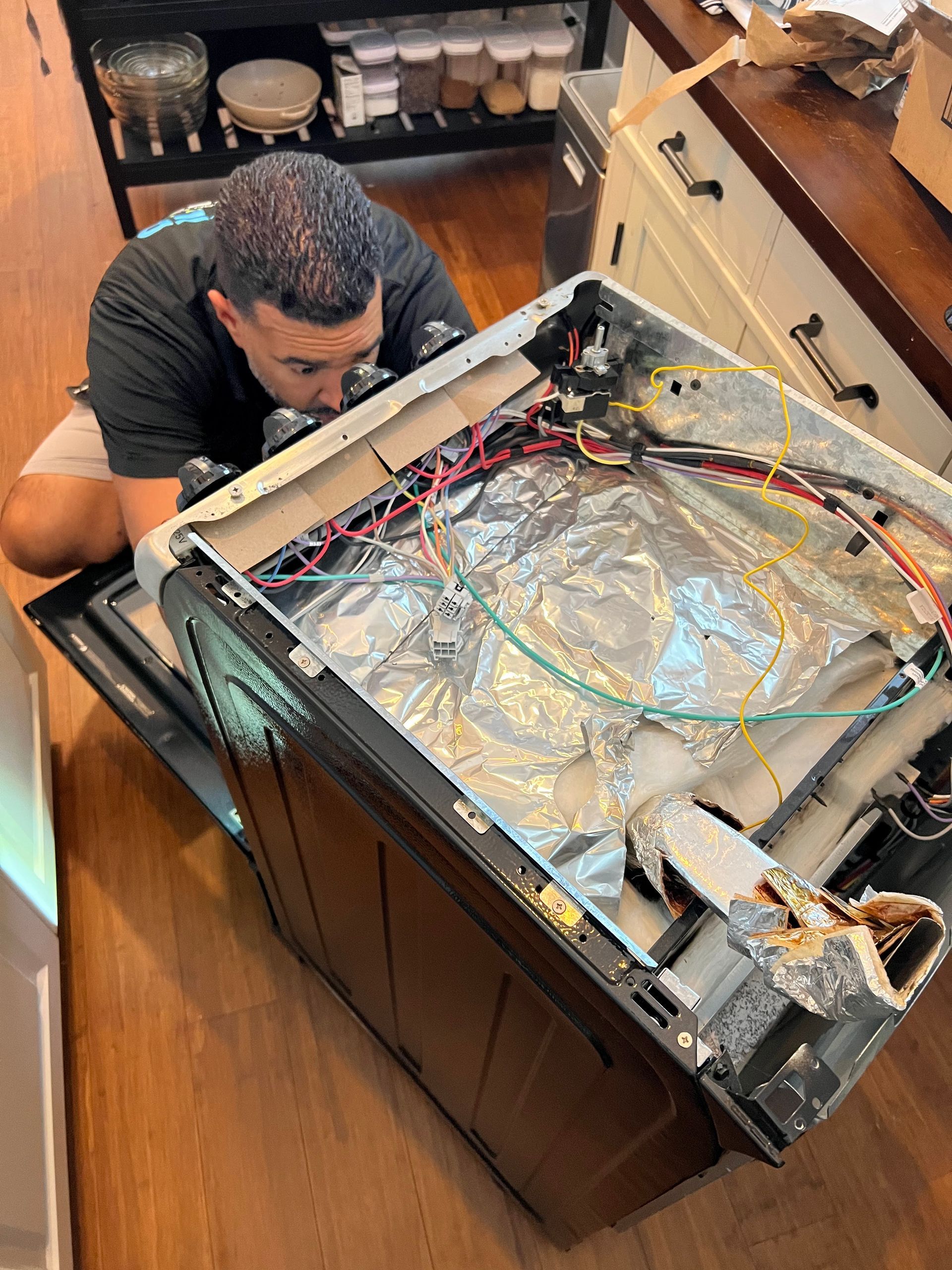 A man is working on an oven in a kitchen.